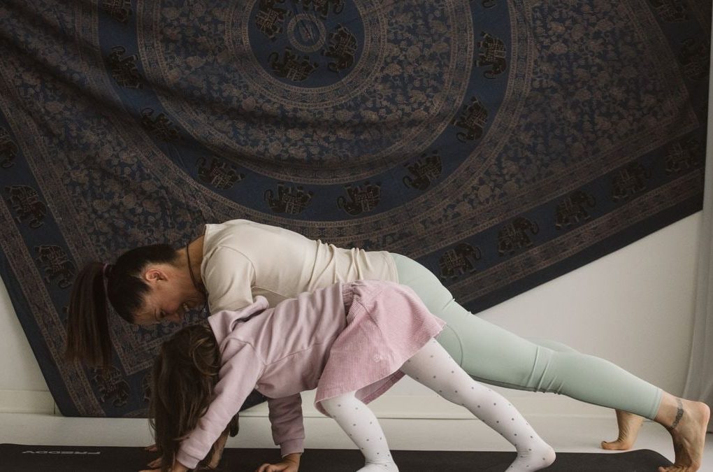 A mother and child practicing yoga together indoors, showcasing family bonding and wellness.